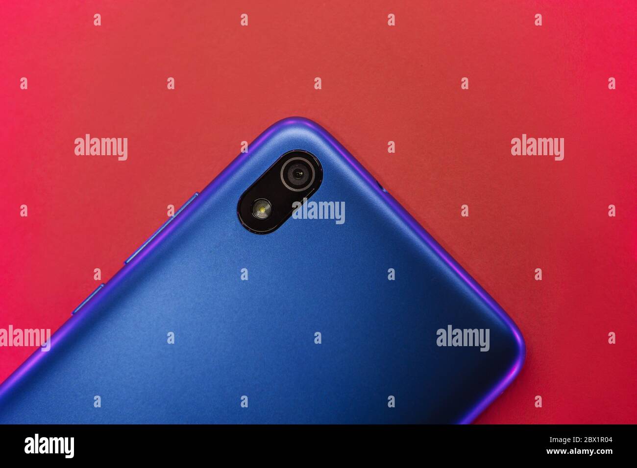 Cellule ou téléphone portable avec caméra sur fond rouge. La couleur néon se trouve sur le couvercle du téléphone Banque D'Images