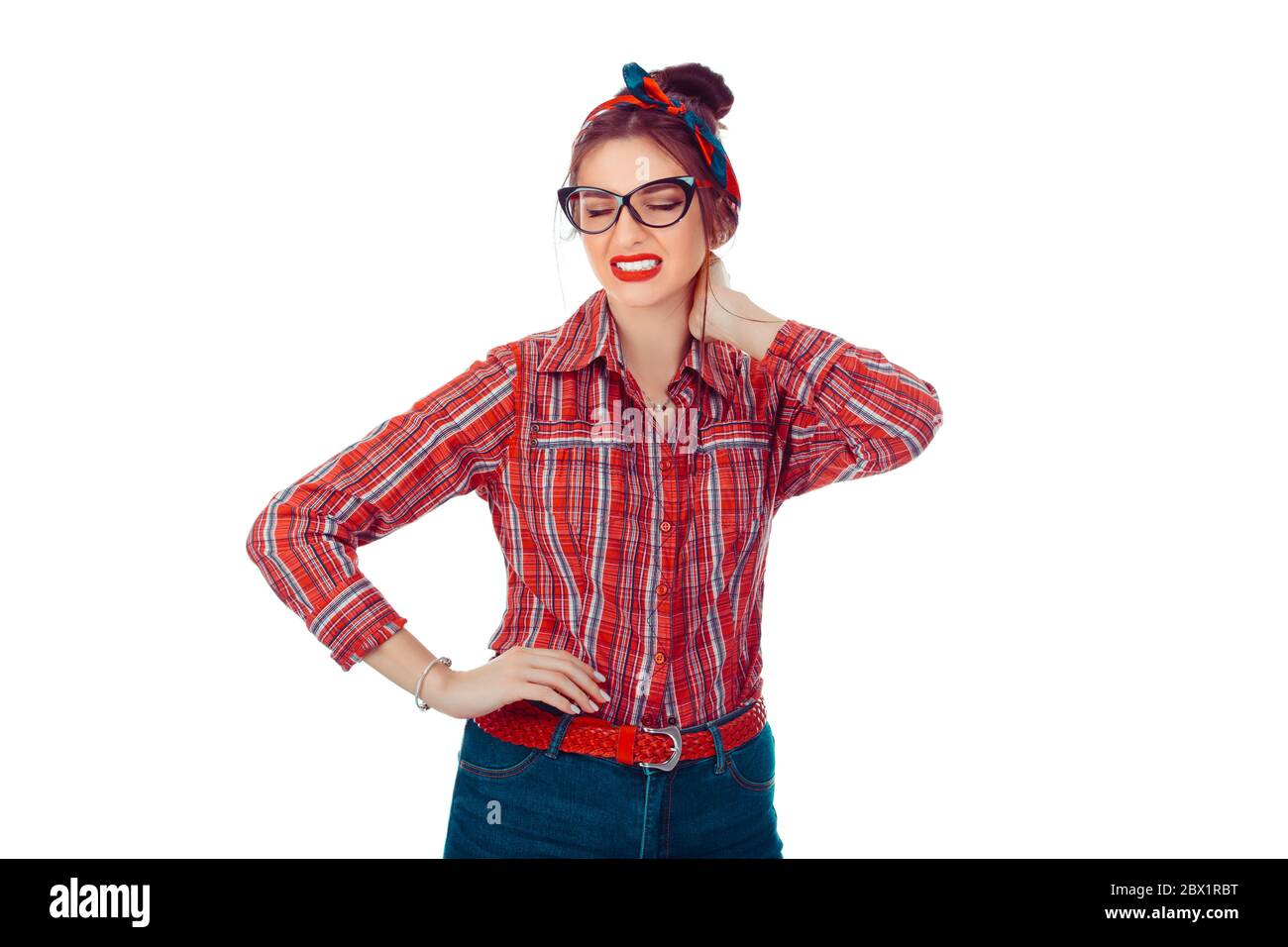 Femme fatiguée ayant un pan dans le cou. Portrait en gros plan d'une belle fille en chemise à carreaux rouges et jeans avec noeud rétro sur la tête isolée sur un ba blanc pur Banque D'Images