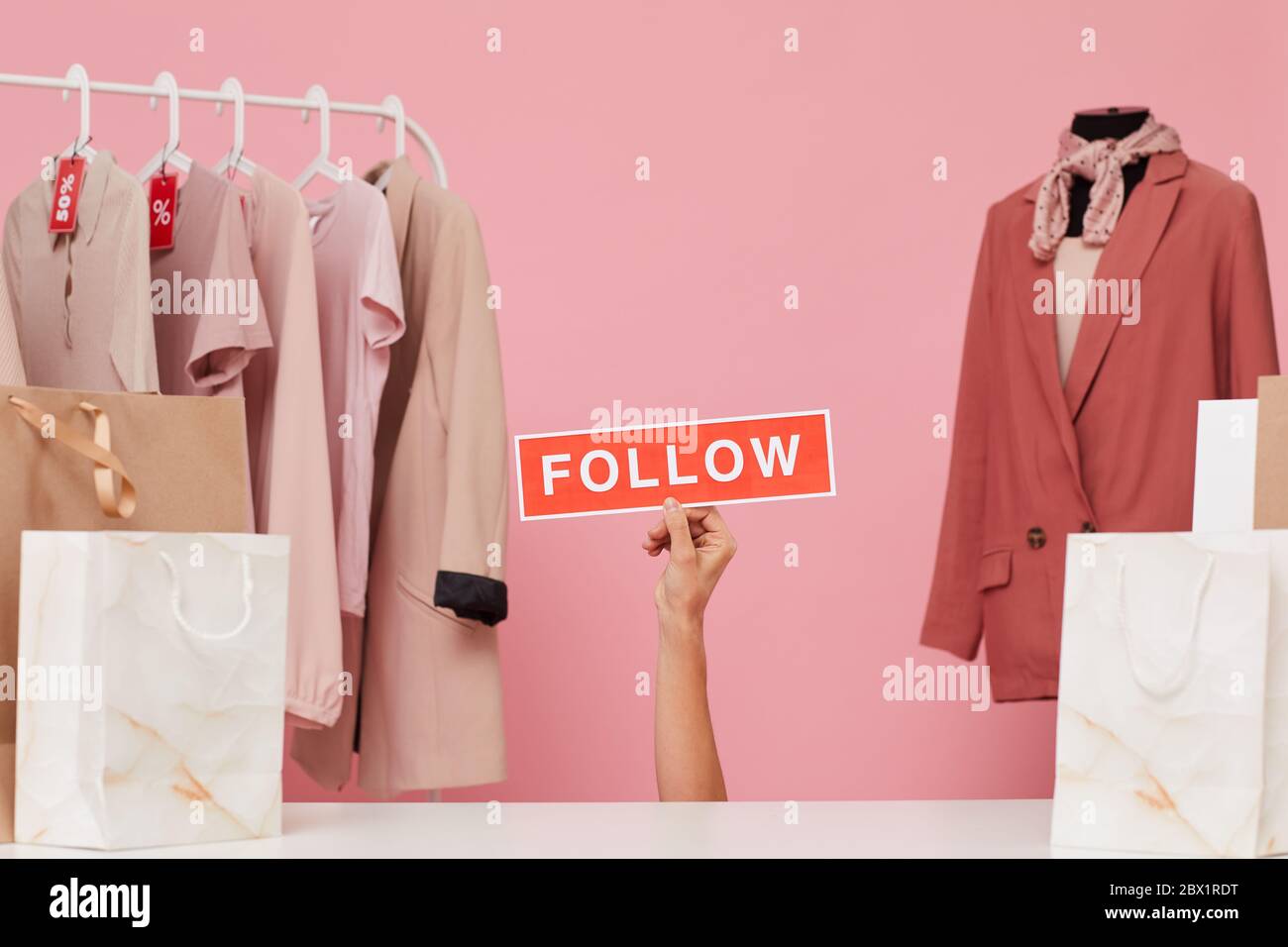 Image de la main de femme tenant l'étiquette et de dire de suivre son magasin de vêtements Banque D'Images