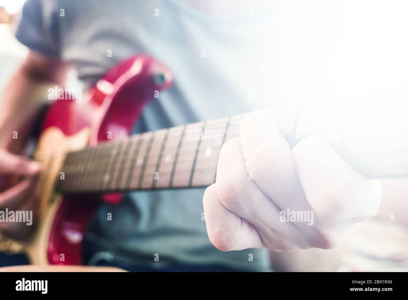 Gros plan de mains masculines jouant de la guitare électrique, Flare from the Sunlight, Selective focus Banque D'Images
