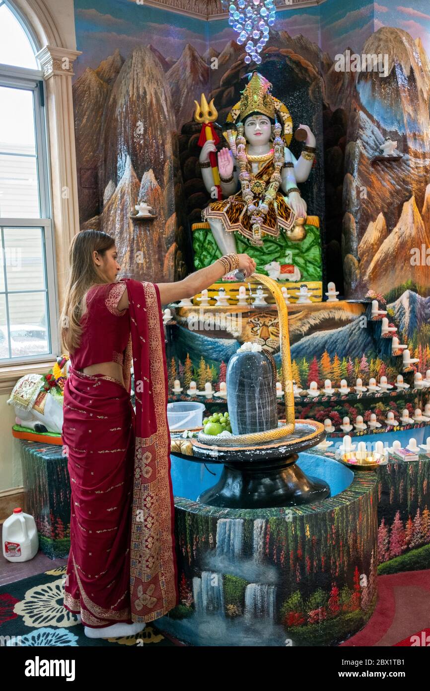 Ann femme hindoue attrayante dans un sari coloré verse du lait sur un shiva lingam. Dans un temple South Richmond Hill, Queens, New York Banque D'Images