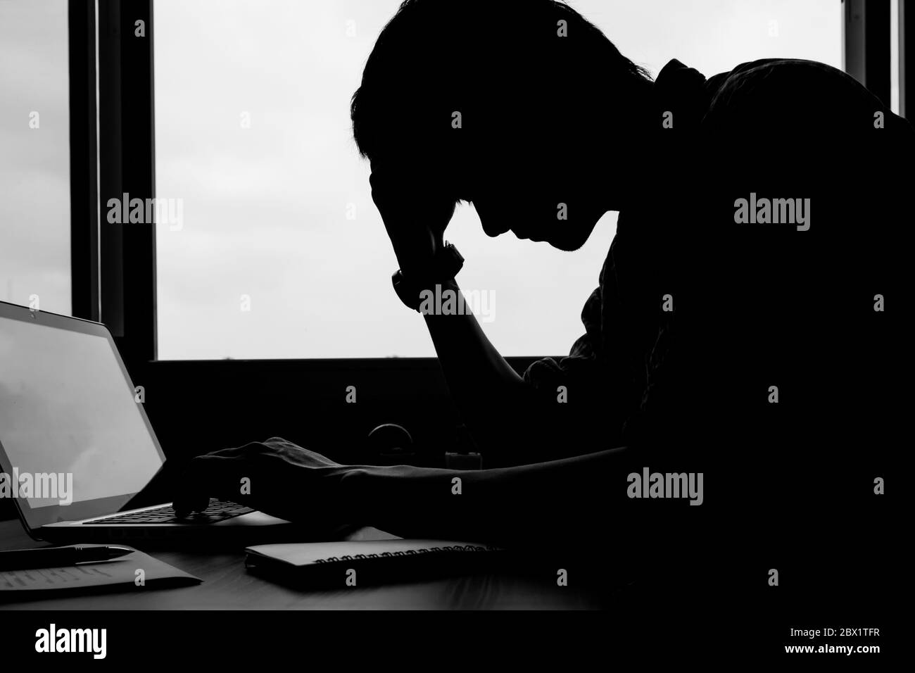 La silhouette d'une image de jeune homme assis sur son bureau. Banque D'Images