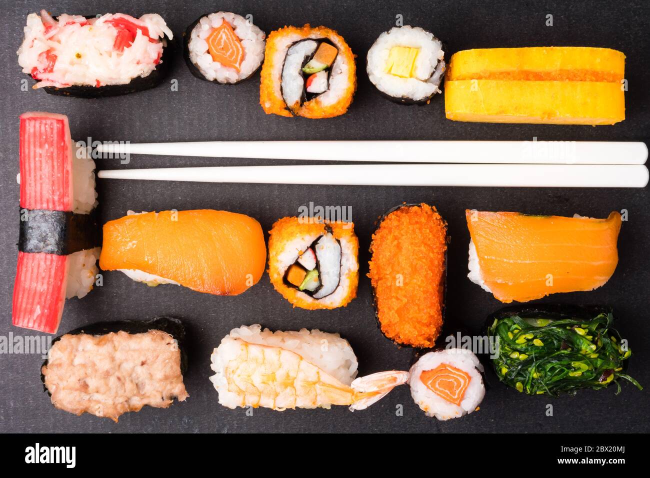 Vue de dessus de l'ensemble de sushi et des baguettes sur fond noir, cuisine japonaise. Banque D'Images