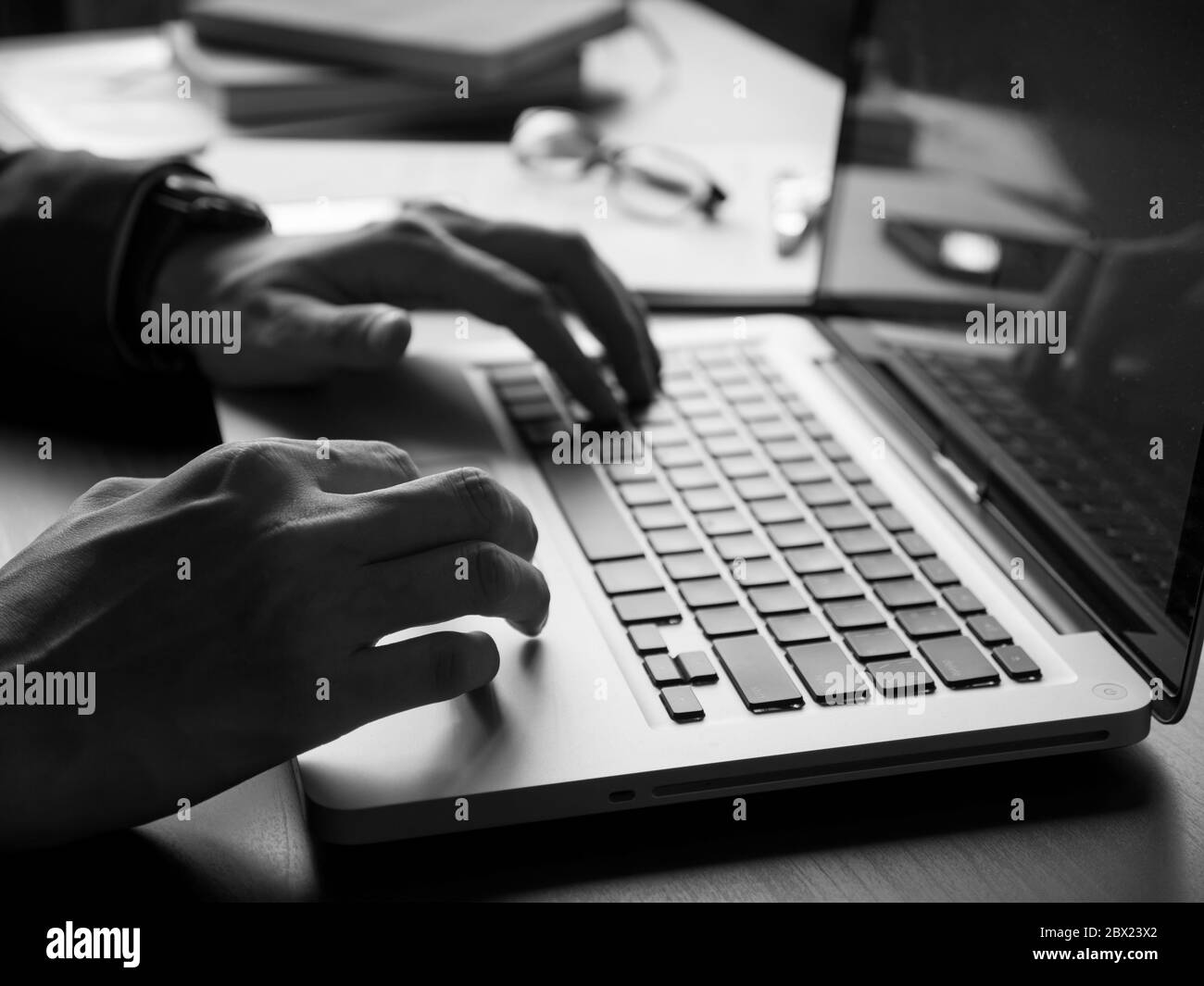Gros plan sur un homme d'affaires utilisant un ordinateur portable sur le bureau. Noir et blanc Banque D'Images