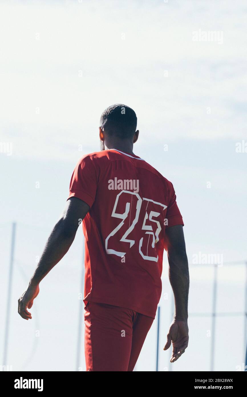 Vue arrière d'un joueur de football afro-américain qui marche sur l'herbe pas Banque D'Images