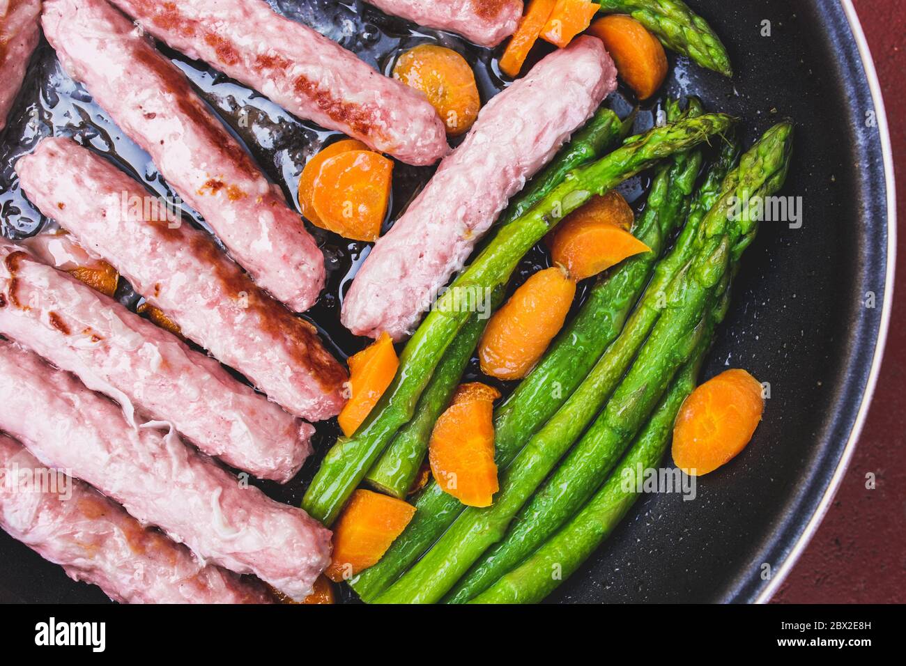 Saucisses de porc avec carottes et asperges dans une casserole - aliments gras à haute teneur en calories Banque D'Images