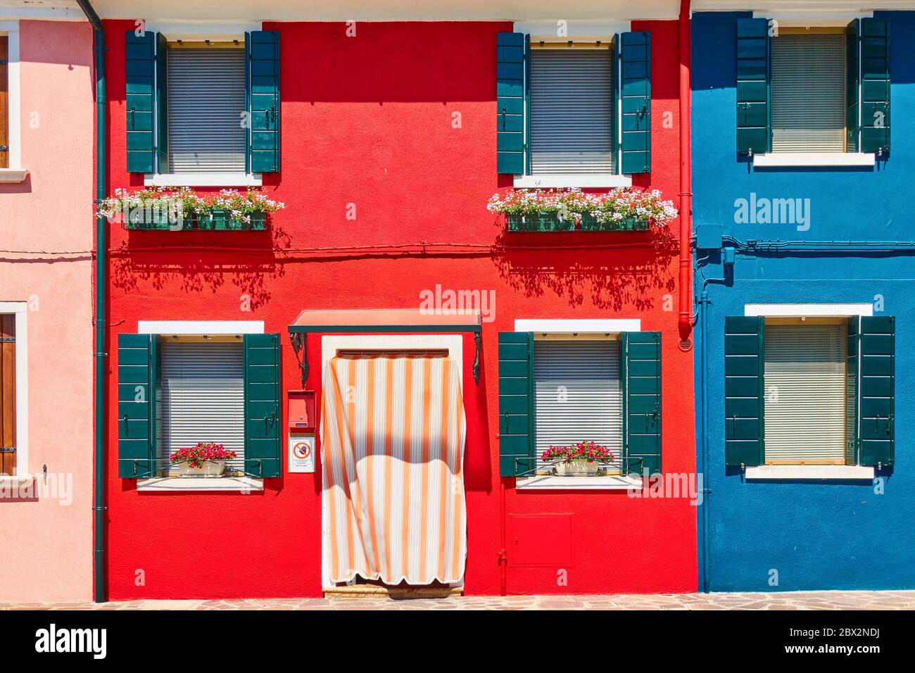 Maisons aux couleurs vives à Burano à Venise avec des fleurs sur les rebords de fenêtre, Italie - architecture italienne Banque D'Images