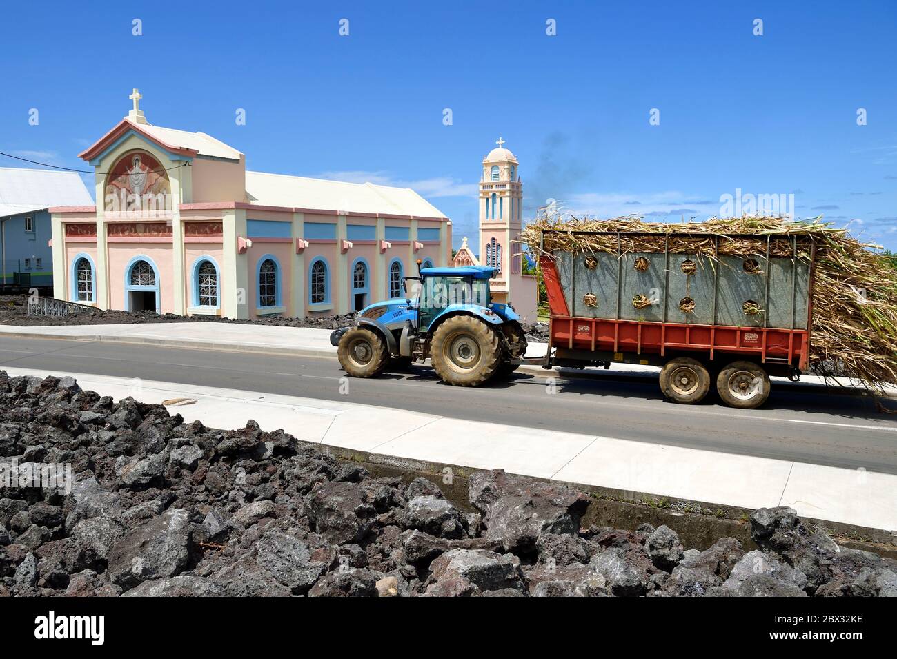 France, Ile de la Réunion (département français d'outre-mer), l'église notre-Dame-des-Laves de Piton Sainte-Rose épargnée par le flux de lave de 1977, tracteur transportant une charge de canne à sucre à l'usine de sucre Banque D'Images