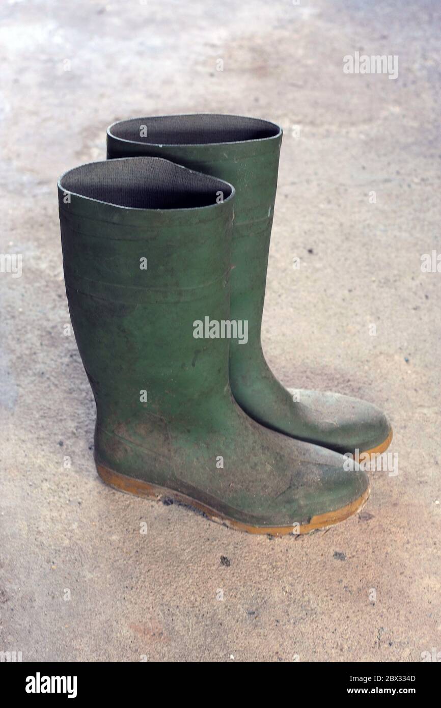 Ancienne paire de bottes Green Wellington (bottes en caoutchouc) sur un sol en béton Banque D'Images