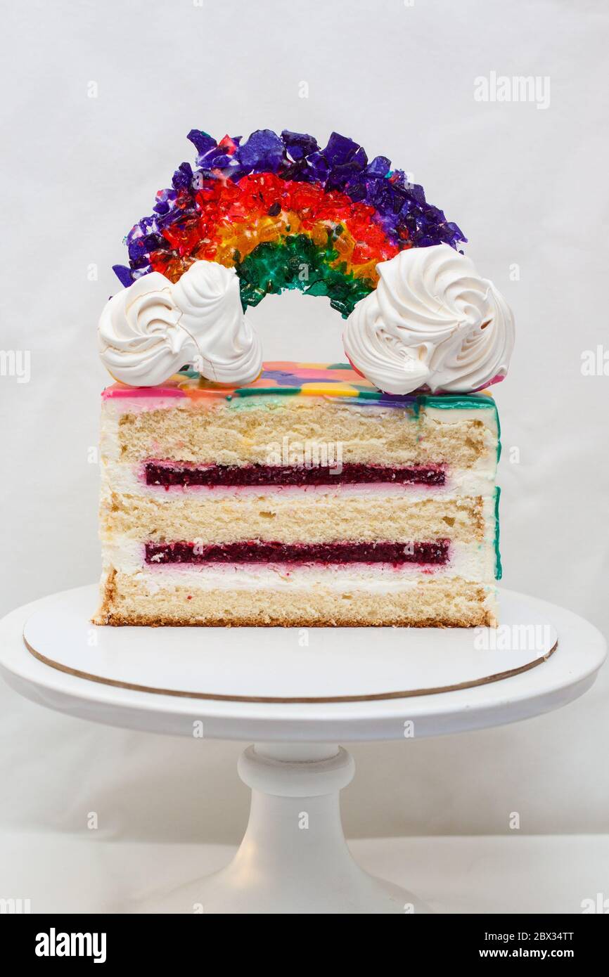 Tranche de gâteau d'anniversaire à la vanille avec garniture aux baies et décoration arc-en-ciel caramel. Arrière-plan ordinaire, espace de copie. Banque D'Images