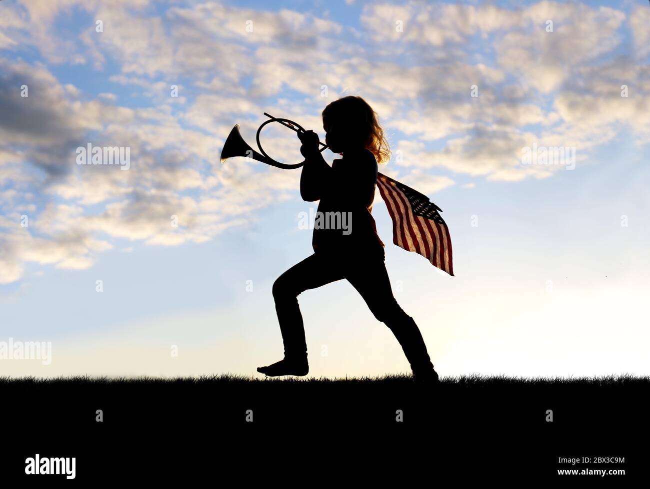 Une silhouette d'une petite fille patriotique jouant et marchant à l'extérieur soufflant une corne française et portant un drapeau américain. Banque D'Images