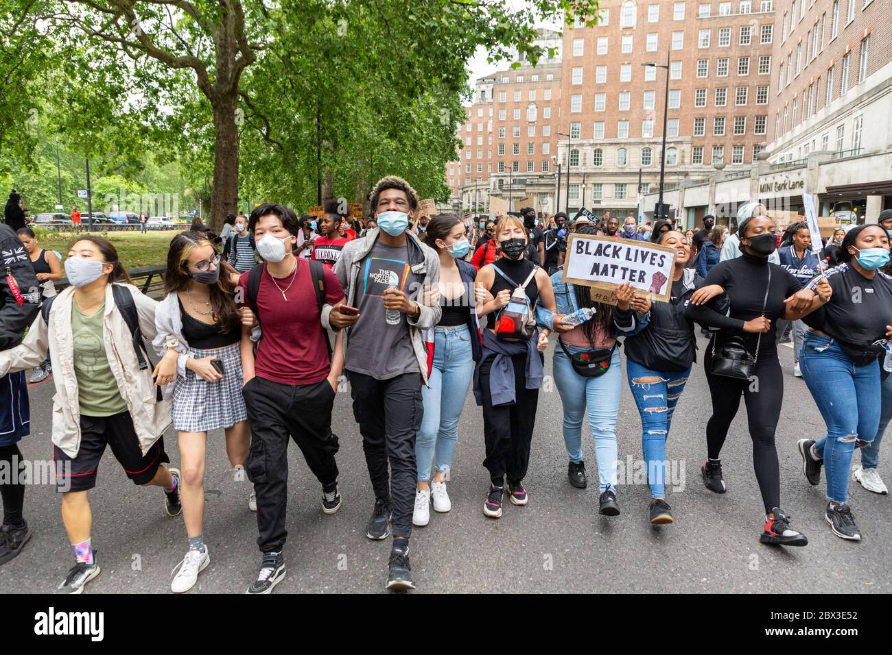De jeunes manifestants marchant avec des armes liées le long d'une route pendant la Black Lives Matters protestent à Londres, le 3 juin 2020 Banque D'Images