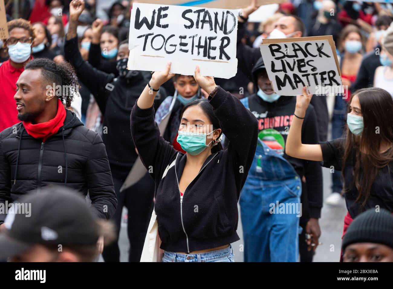 Une fille asiatique tient un panneau tout en marchant à la Black Lives Matters manifestation à Londres, le 3 juin 2020 Banque D'Images