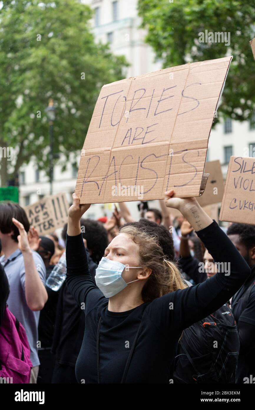 Une femme blanche qui prend le genou et tient un panneau pendant la Black Lives Matters proteste devant 10 Downing Street, Londres, 3 juin 2020 Banque D'Images