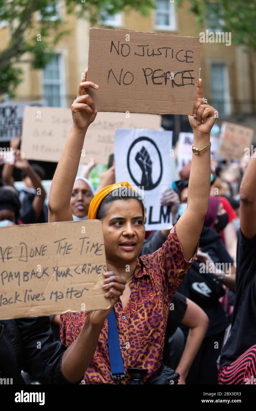 Une femme qui prend le genou et tient un panneau pendant la Black Lives Matters proteste devant 10 Downing Street, Londres, 3 juin 2020 Banque D'Images