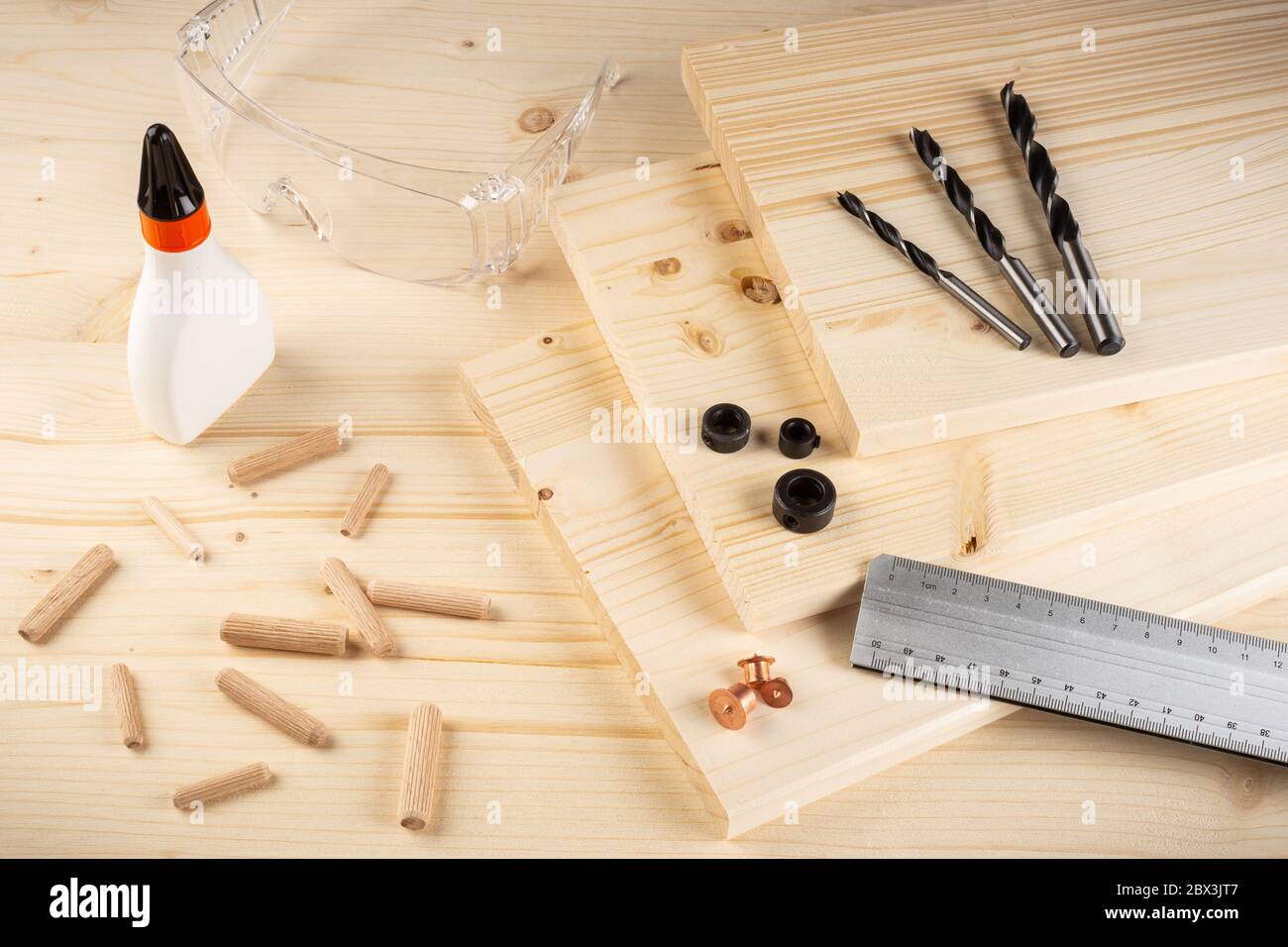 goupilles de joint de cheville en bois tiges de perçage colle bois planches lunettes de sécurité et outils sur fond d'épinette. Concept de fabrication de mobilier de l'industrie du menuisier. Banque D'Images