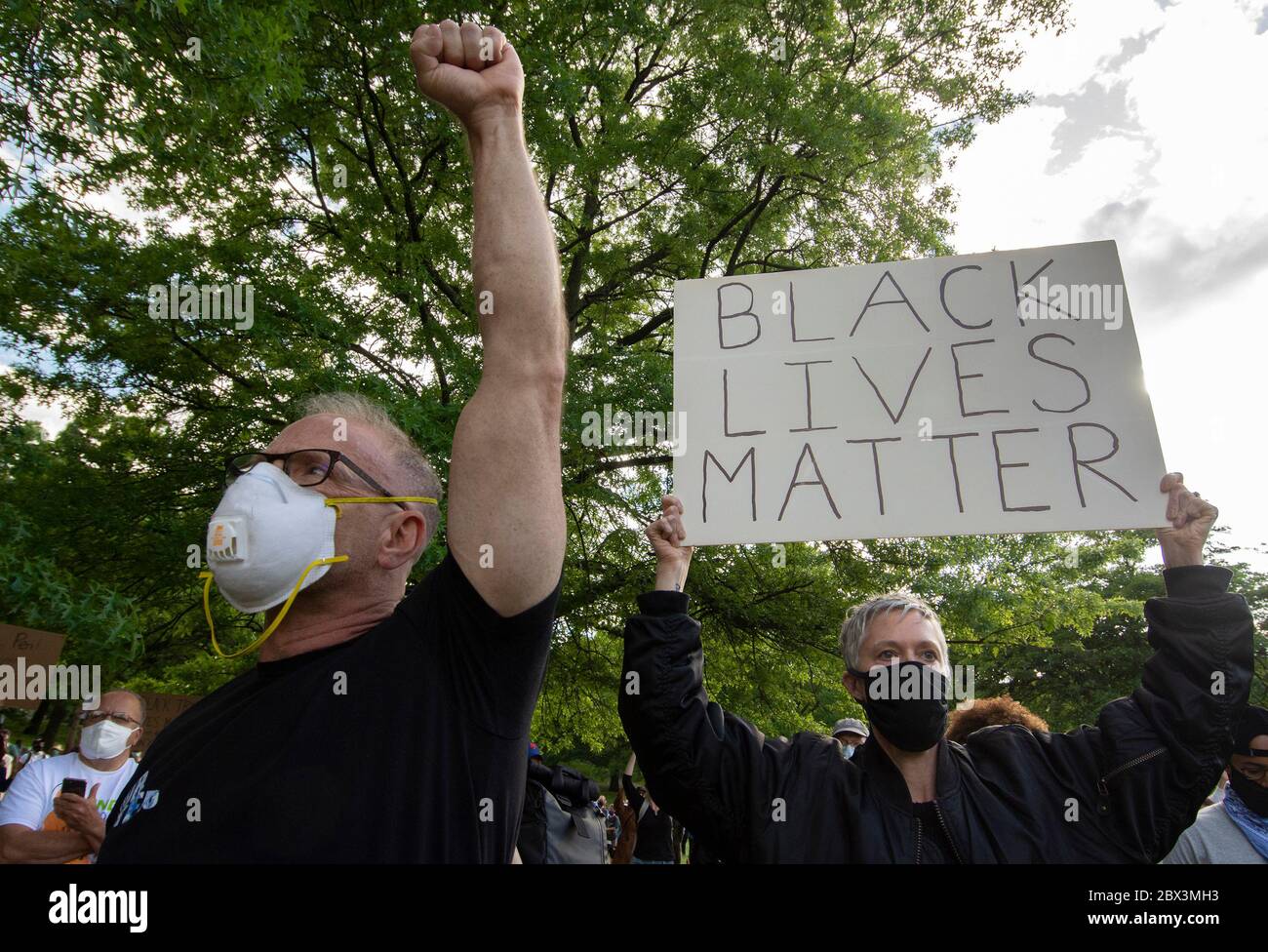 Un homme tient un poing élevé comme signe de solidarité avec la communauté afro-américaine comme une femme tient un signe de soutien pendant une vigile et se réunit pour George Floyd dimanche, 31 mai 2020, à Inwood Park dans le quartier de Manhattan de New York. Floyd a été tué pendant sa détention provisoire à Minneapolis, en mai 25. (Shoun A. Hill) Banque D'Images