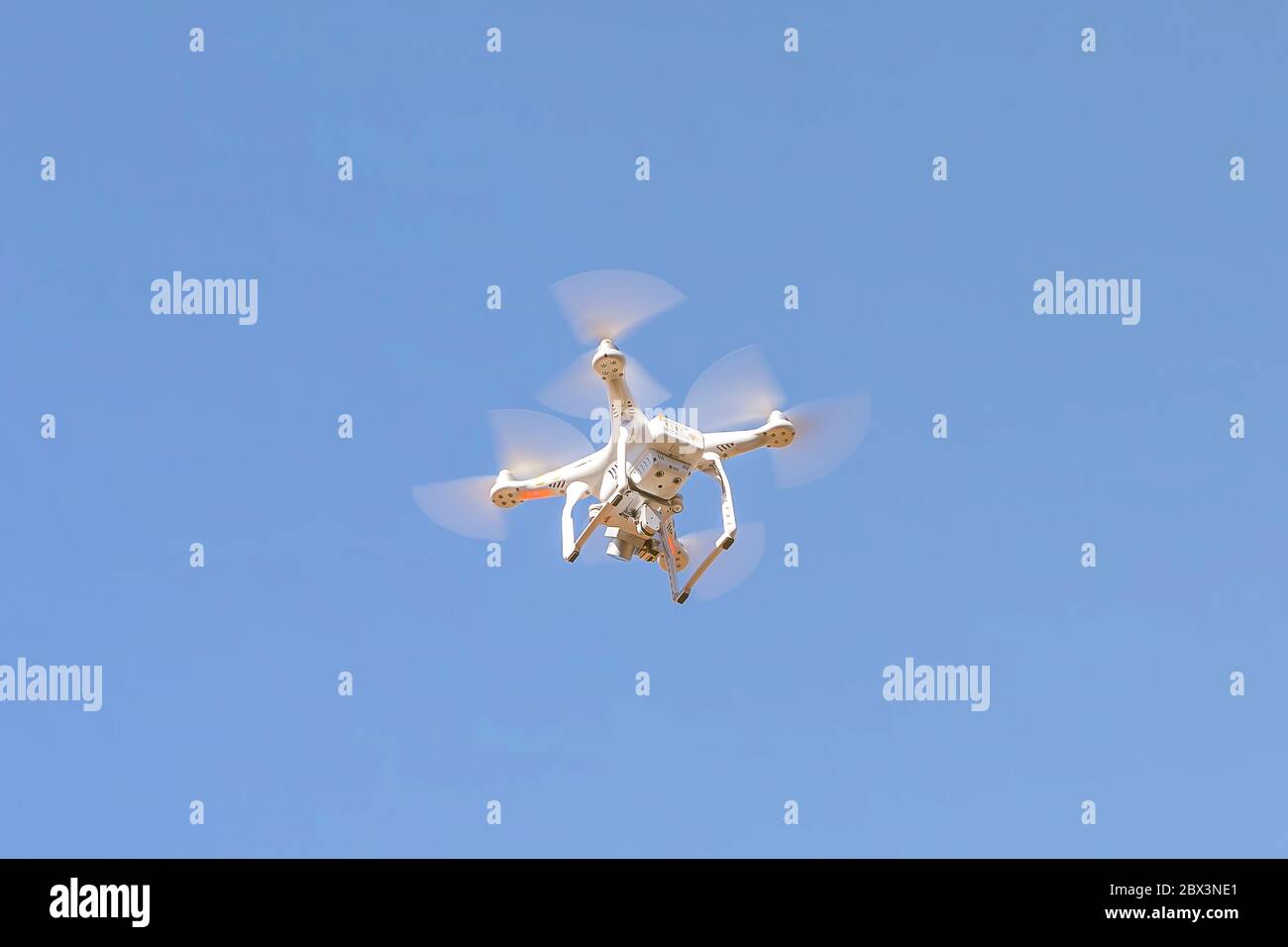Un flic de drone volant dans le ciel bleu vif de l'été avec un appareil photo numérique Banque D'Images