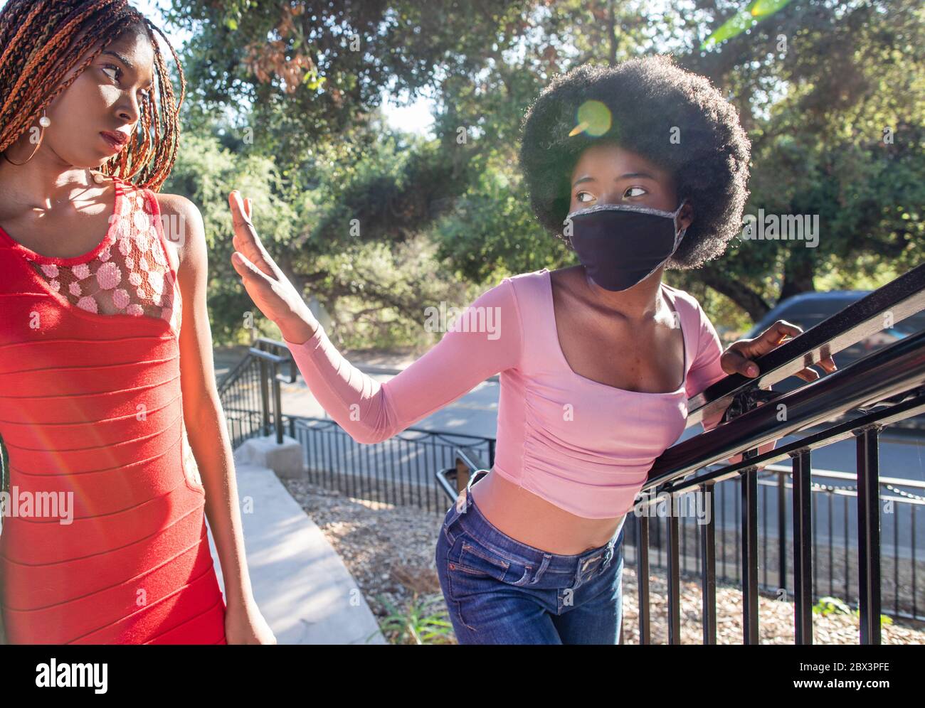 Une fille portant un masque de visage essaie de rester loin d'une personne sans masque dans la rue. Les masques sont obligatoires dans de nombreux pays en raison de la COVID-19 Banque D'Images