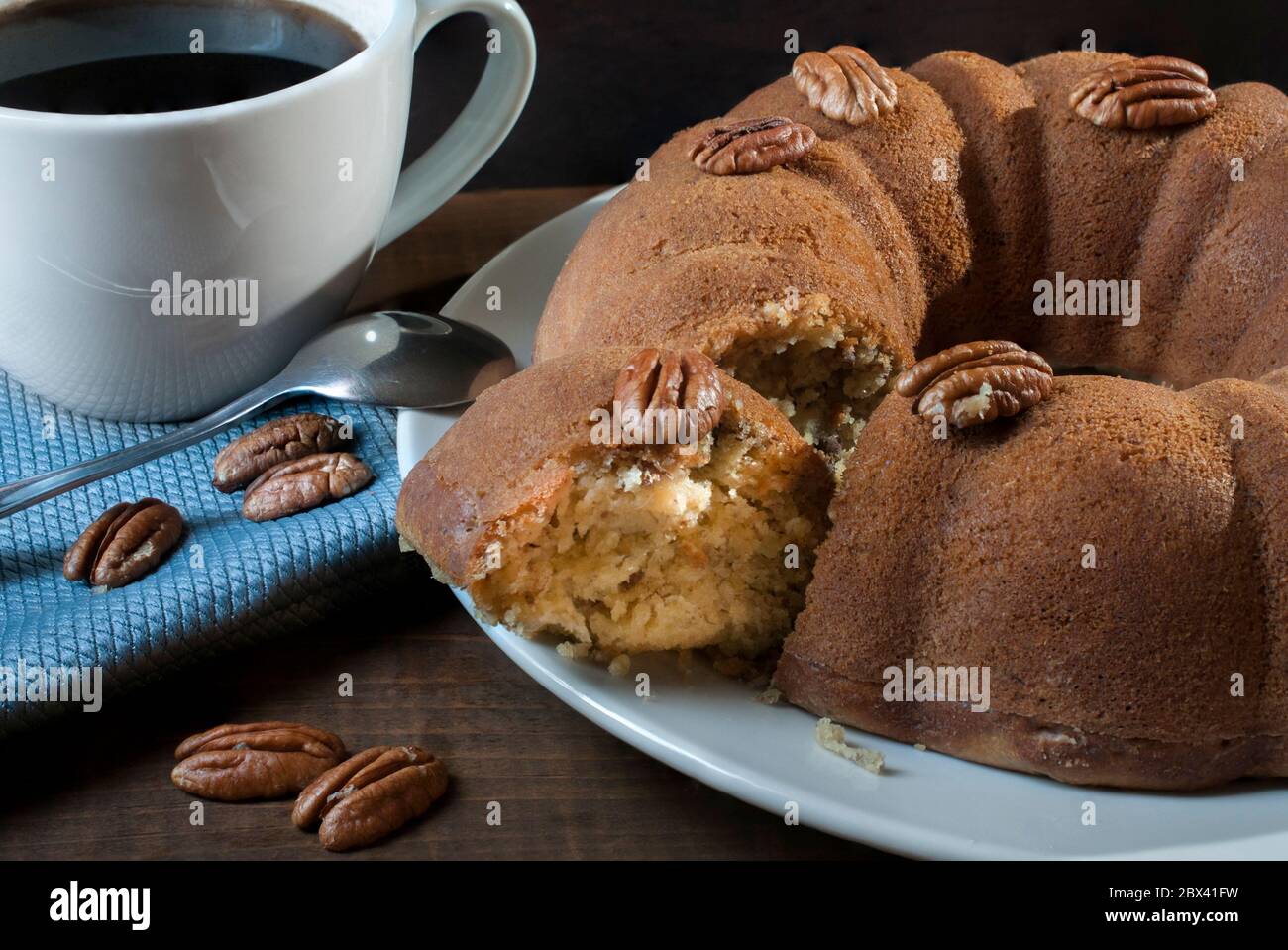 Une Tranche De Gateau En Forme De Bague De Noix Sur Une Assiette Blanche Et Des Noix Sur Le Gateau Et Dans Une Serviette Bleue Avec Une Tasse Blanche Ou Une Tasse