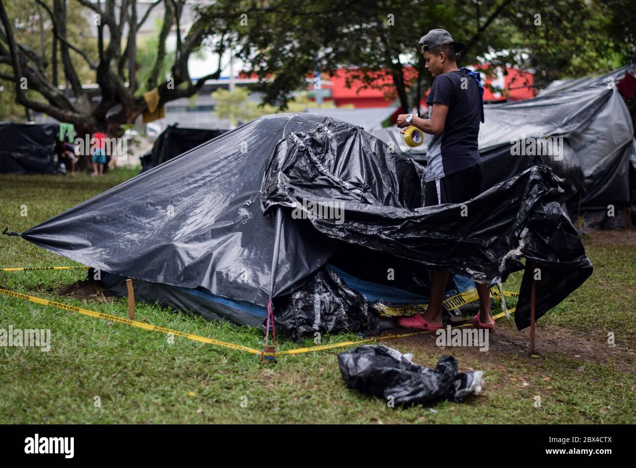 Les Vénézuéliens bloqués construisent un camp de fortune dans un parc couvert d'arbres au milieu de la pandémie de Covid-19, en attendant l'occasion de retourner dans leur pays, Cali, Banque D'Images