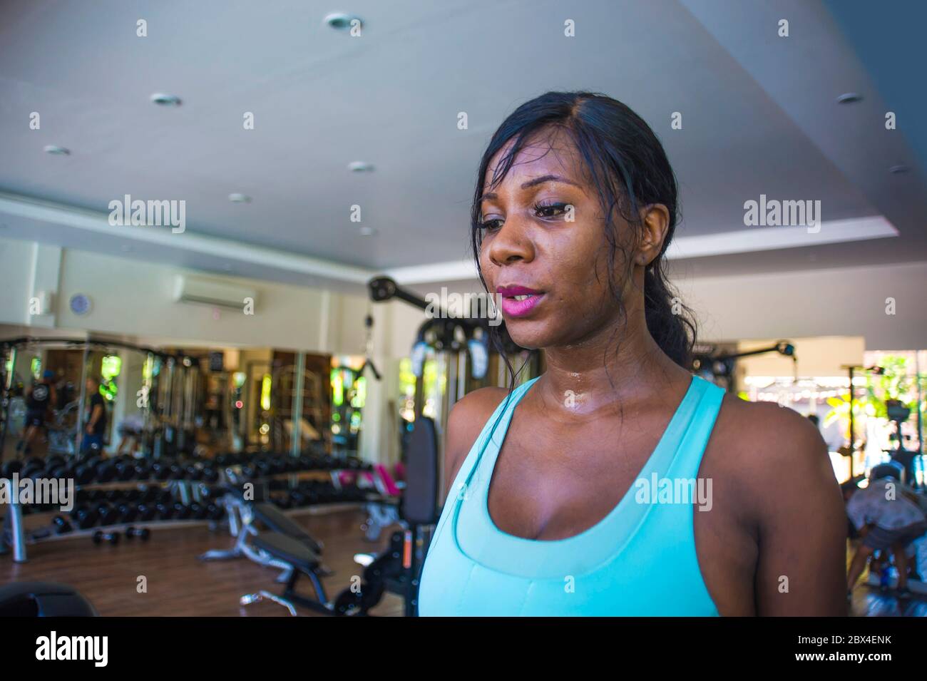 Gros plan style de vie à l'intérieur portrait de jeune femme afro-américaine noire et sueur s'entraîner dur au club de fitness marchant se rafraîchir après h Banque D'Images