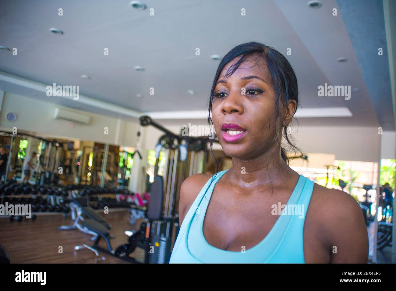 Gros plan style de vie à l'intérieur portrait de jeune femme afro-américaine noire et sueur s'entraîner dur au club de fitness marchant se rafraîchir après h Banque D'Images