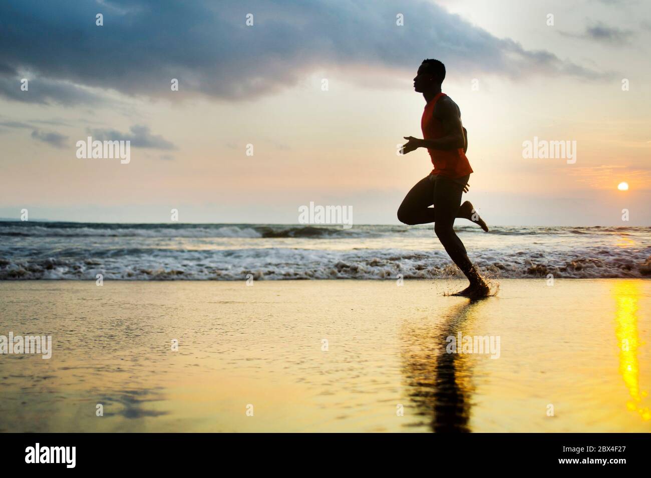 Silhouette de jeune coupe attrayante athlétique et noir fort afro américain courir au coucher du soleil plage entraînement dur et sprinting sur l'eau de mer en pro Banque D'Images