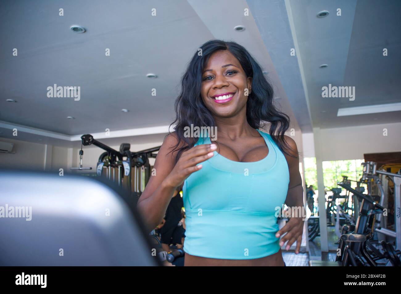 Intérieur gym portrait de jeune attrayant et heureux noir afro-américain sportif femme entraînement tapis roulant entraînement à la séance d'entraînement au club de fitness dans les soins du corps Banque D'Images