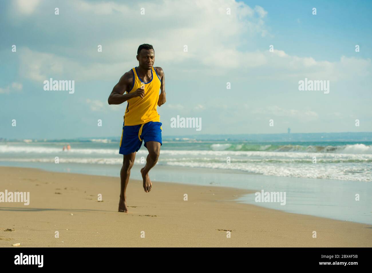 Jeune coupe attrayante athlétique et fort noir Africain américain homme courant à la plage entraînement dur et sprint sur l'eau de mer dans professionnel athl Banque D'Images