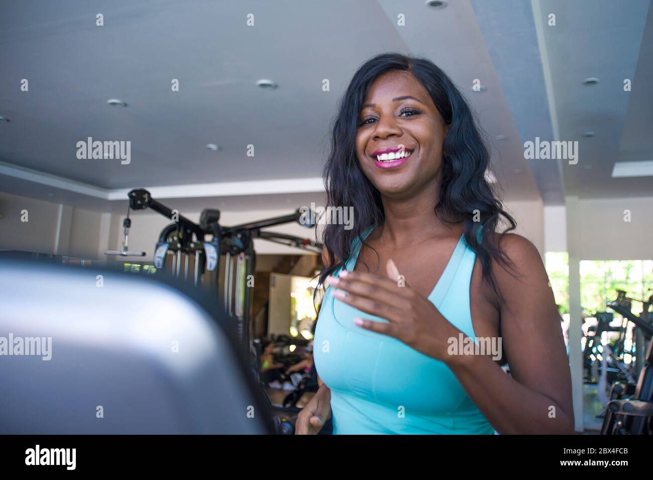 Intérieur gym portrait de jeune attrayant et heureux noir afro américaine sportive femme entraînement tapis roulant entraînement à la séance d'entraînement au club de fitness dans les soins du corps an Banque D'Images
