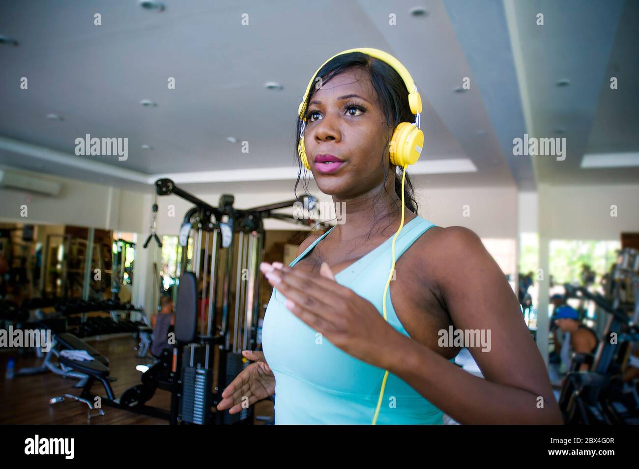Intérieur gym portrait de jeune femme afro-américaine noire attrayante avec casque d'entraînement dur un tapis roulant dur d'entraînement à la forme physique club dans b Banque D'Images