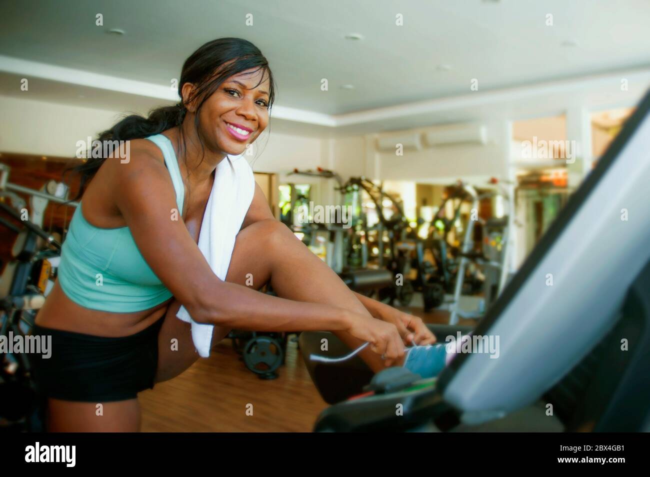 Portrait intérieur de jeune attrayant et heureux noir afro American femme entraînement à la salle de gym cravates chaussures de sport après l'entraînement de course dur de course sueur Banque D'Images