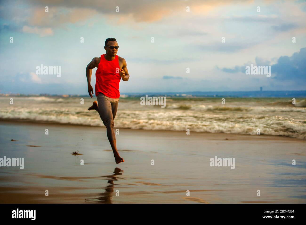Jeune coupe attrayante athlétique et fort noir afro américain homme courant à la plage entraînement dur et sprinting sur l'eau de mer en athlète professionnel Banque D'Images