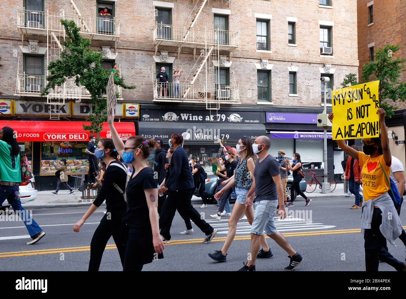 New York, NY 2 juin 2020. Les gens qui observent un immeuble d'appartements sur York Avenue dans l'Upper East Side de Manhattan applaudissent à une marche de la Black Lives quand elle passe par leurs fenêtres. Un marcheur porte un signe, 'Ma couleur de peau n'est pas UNE arme'. Les manifestants marchent en solidarité avec d'autres personnes dans tout le pays en appelant à la justice dans une série récente de meurtres de la police américaine : George Floyd, Breonna Taylor et d'innombrables autres. Des milliers de personnes se sont jointes à la marche depuis Foley Square, s'arrêtant près de Gracie Mansion, la maison du maire de New York, avant de déménager à Times Square plus tard. 2 juin 20 Banque D'Images