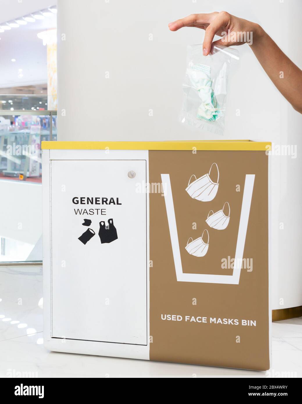 Les gens lancent main masque médical de visage couvert avec sac en plastique dans un bac à la galerie marchande. La bonne façon de protéger le coronavirus ou le concept Covid-19. Banque D'Images