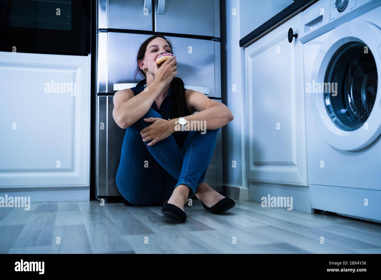 Douceur. Les femmes manger la nuit près du réfrigérateur Banque D'Images