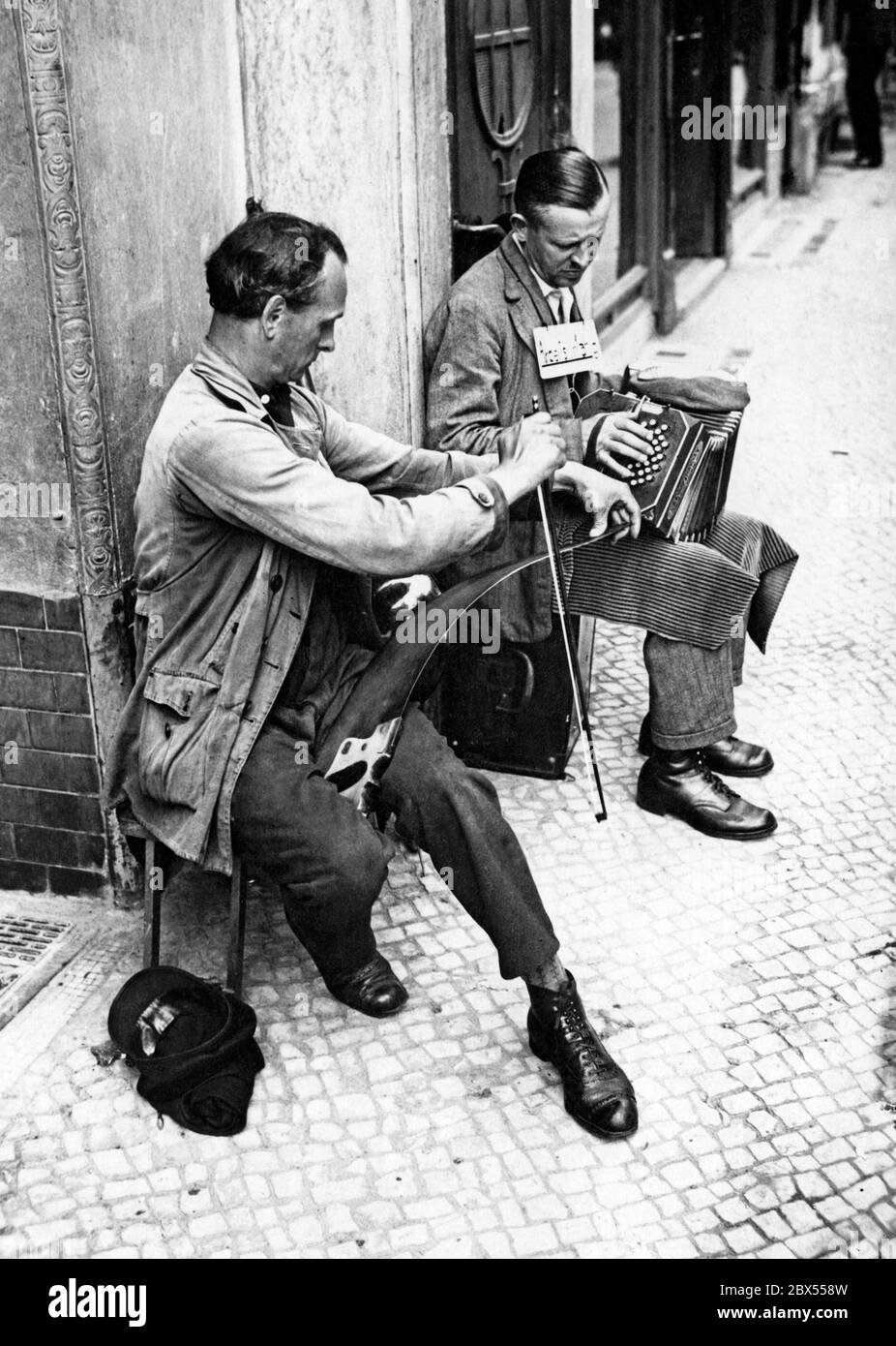 Deux musiciens de rue pendant leur jeu. Le gauche joue sur la "scie à cloche", un instrument populaire et bon marché, le droit sur un accordéon. Banque D'Images