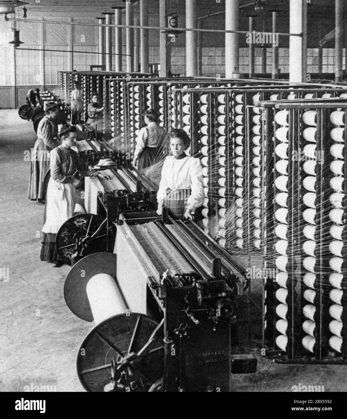 Dans une filature de coton, les travailleuses utilisent les machines de filature qui serpentent le fil dans le tissu. La photo a été prise en 1905. Banque D'Images