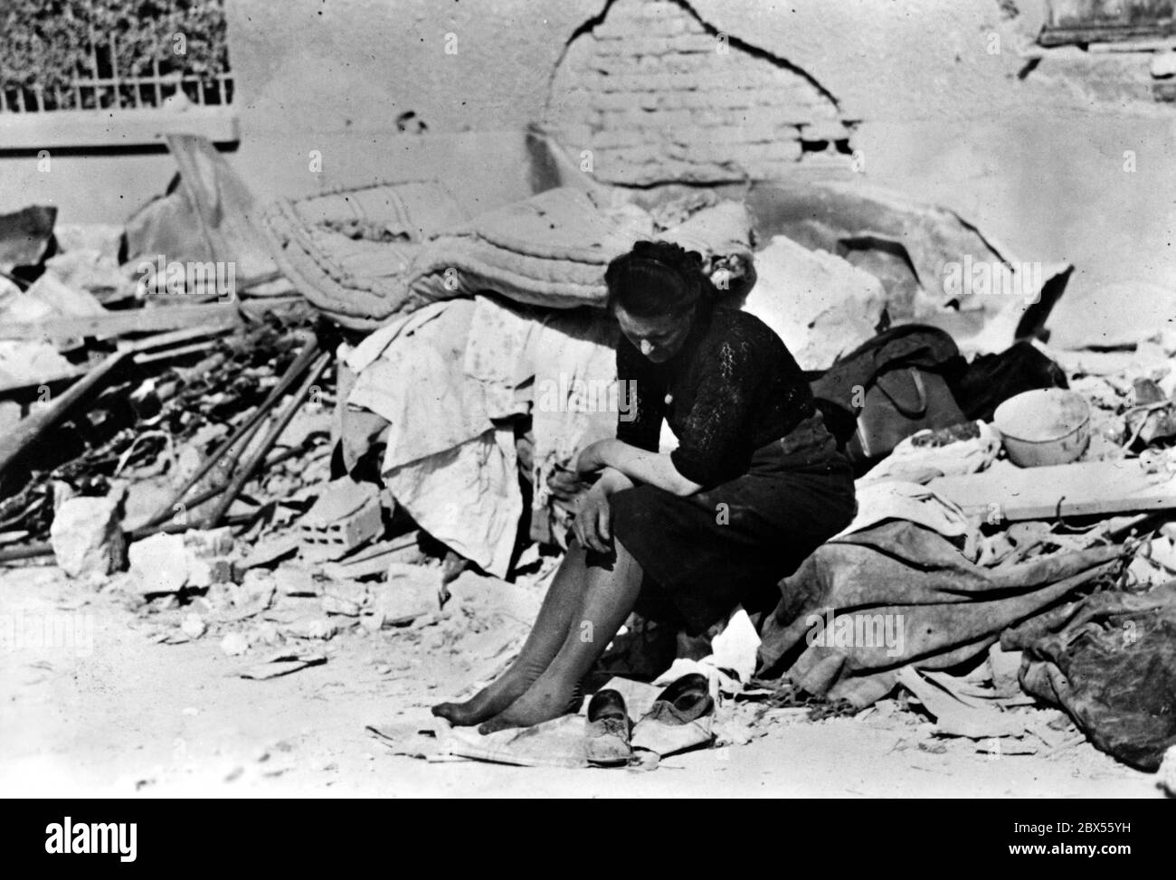 Une femme est assise sur les ruines d'une maison. Ses chaussures sont à côté d'elle. Auparavant, les bombardiers anglo-américains ont effectué un raid aérien à Paris et, entre autres, sur le circuit de Longchamps, tuant de nombreux civils. Banque D'Images