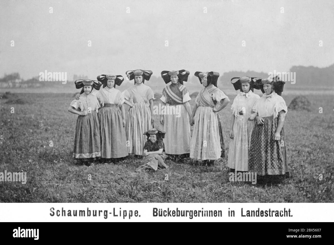 La photo de 1903 montre des femmes et des filles en costume traditionnel de Bueckeburg de la région de Schaumburg-Lippe dans la Basse-Saxe d'aujourd'hui. Les grands cache-nœud ou le gros cache-nœud noir (Fluegelhauben) et les tabliers colorés sont particulièrement frappants. Banque D'Images