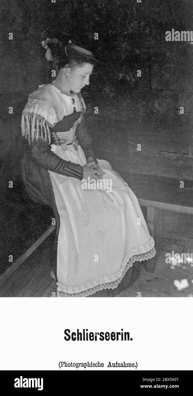 Une fille de la ville bavaroise de Schliersee en costume traditionnel est assise avec dégoût sur un banc. Banque D'Images