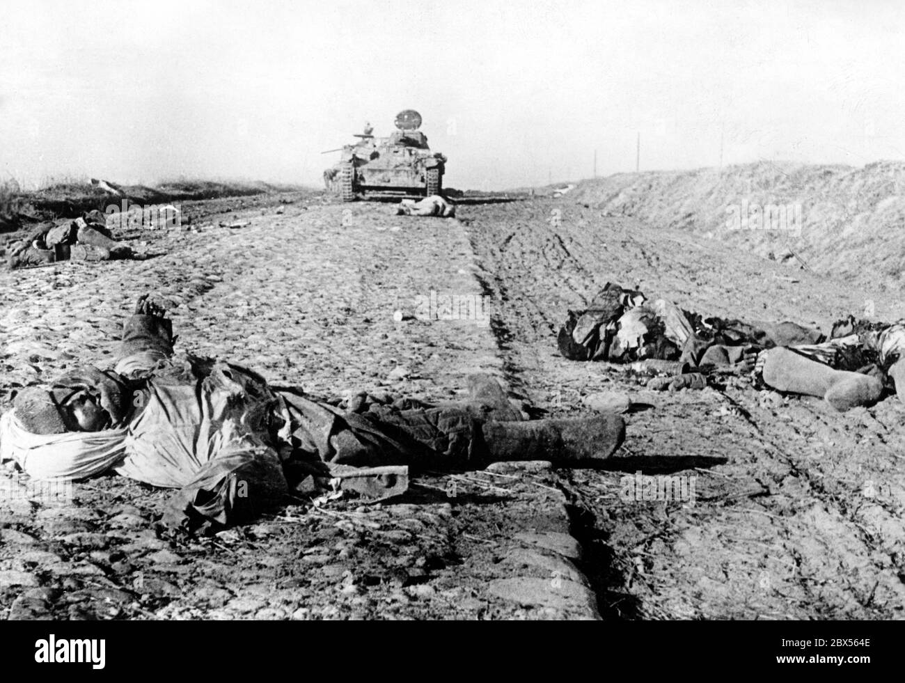 Les corps de soldats soviétiques sont sur une route non pavée. En arrière-plan, il y a un réservoir détruit par un pistolet anti-char allemand. Pendant la bataille d'encerclement de Kholm, le 'Kampfgruppe Scherer' a défendu avec succès la ville pendant 105 jours. (Photo PK prise par le correspondant de guerre Richard Muck qui a volé dans la poche au début du mois de mars). Banque D'Images