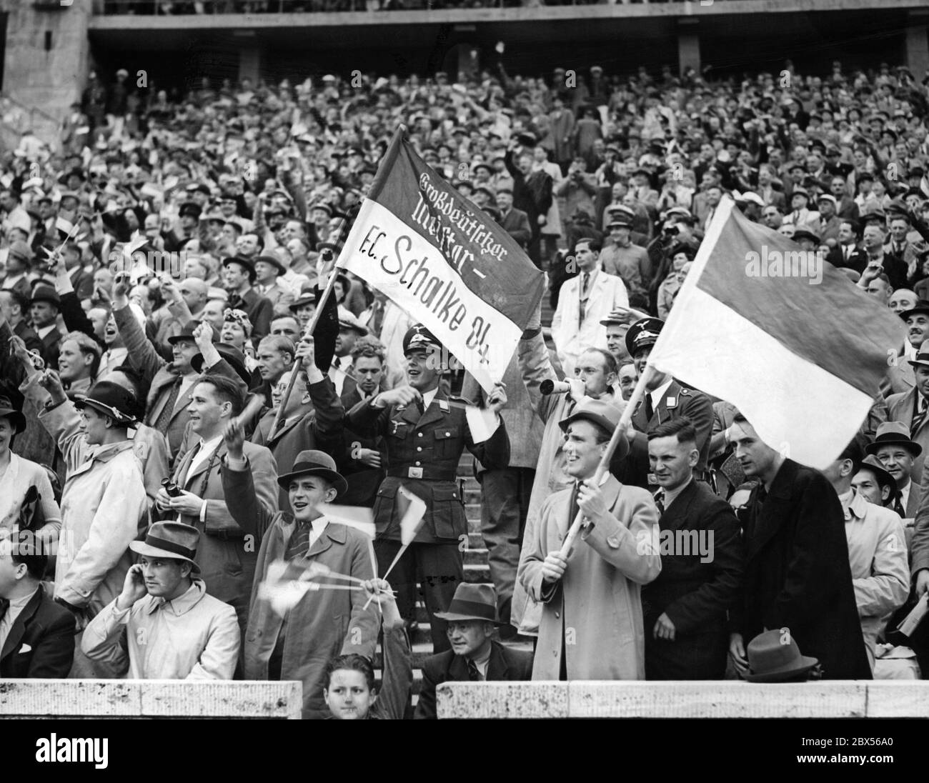 Les fans du FC Schalke 04 applaudissent pour leur équipe lors de la finale du championnat allemand de football contre Admira Wien au stade olympique de Berlin. Un soldat de la Luftwaffe fait le drapeau avec l'inscription Schalke 04 - Grand champion allemand. Au milieu se trouvent deux soldats de la Luftwaffe. Banque D'Images