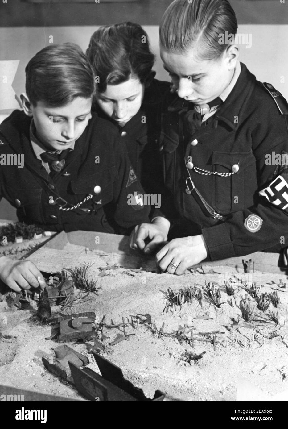 Trois élèves de la 7e année de la 6e école municipale de Potsdam dans l'uniforme de la Jungvolk à leur travail de bac à sable pour l'exposition 'a tenu un den Sandkasten' de l'Association nationale socialiste des enseignants (Administration Reich, Bureau de liaison Berlin). Ils ont présenté la défense de l'échec de la tentative d'atterrissage à Dieppe. Banque D'Images