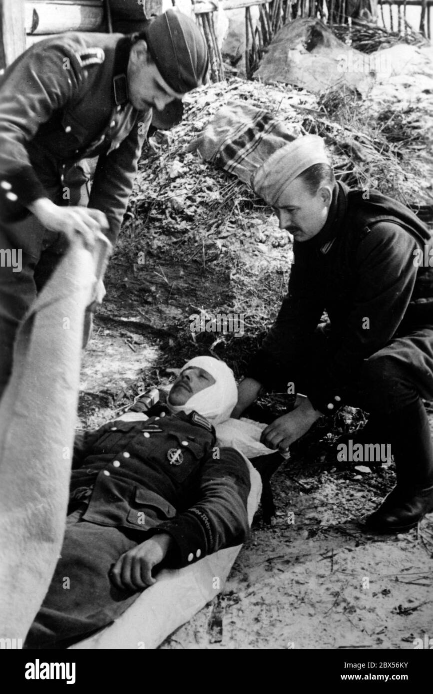 Un fonctionnaire allemand blessé est placé sur une civière par deux autres. Pendant la bataille d'encerclement de Kholm, le 'Kampfgruppe Scherer' a défendu avec succès la ville pendant 105 jours. (Photo de la compagnie de propagande (PK) par le correspondant de guerre Richard Muck, qui a pris l'avion dans la poche au début du mois de mars). Banque D'Images