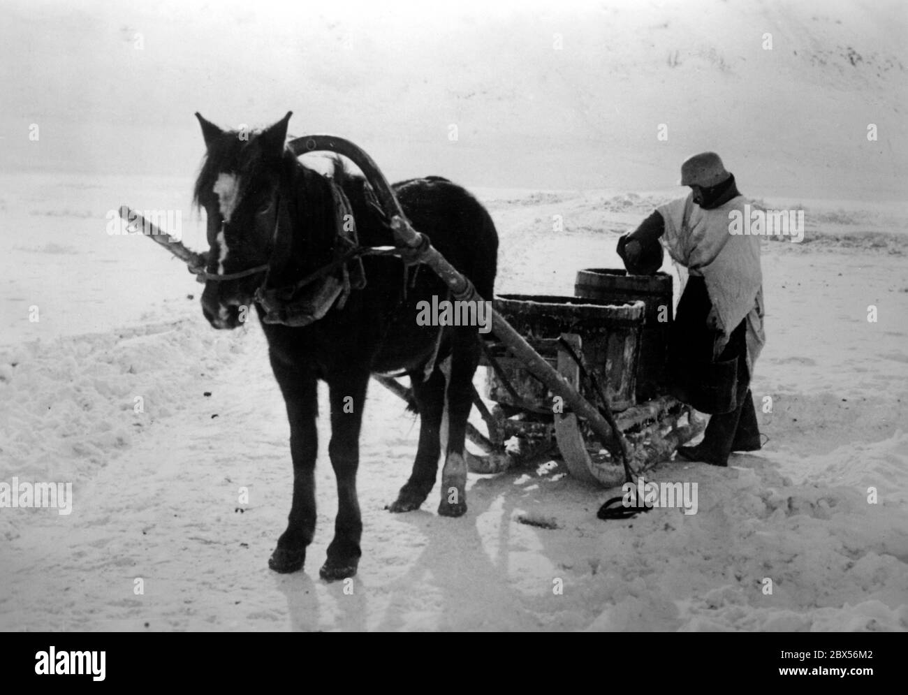 Un soldat allemand utilise un seau pour remplir le canon placé sur un traîneau tiré par des chevaux avec de l'eau douce de la rivière Lovat près de Kholm. Pendant la bataille d'encerclement de Kholm, le 'Kampfgruppe Scherer' a défendu avec succès la ville pendant 105 jours. (Photo PK du correspondant de guerre Richard Muck, qui s'est envolé dans la poche au début du mois de mars). Banque D'Images