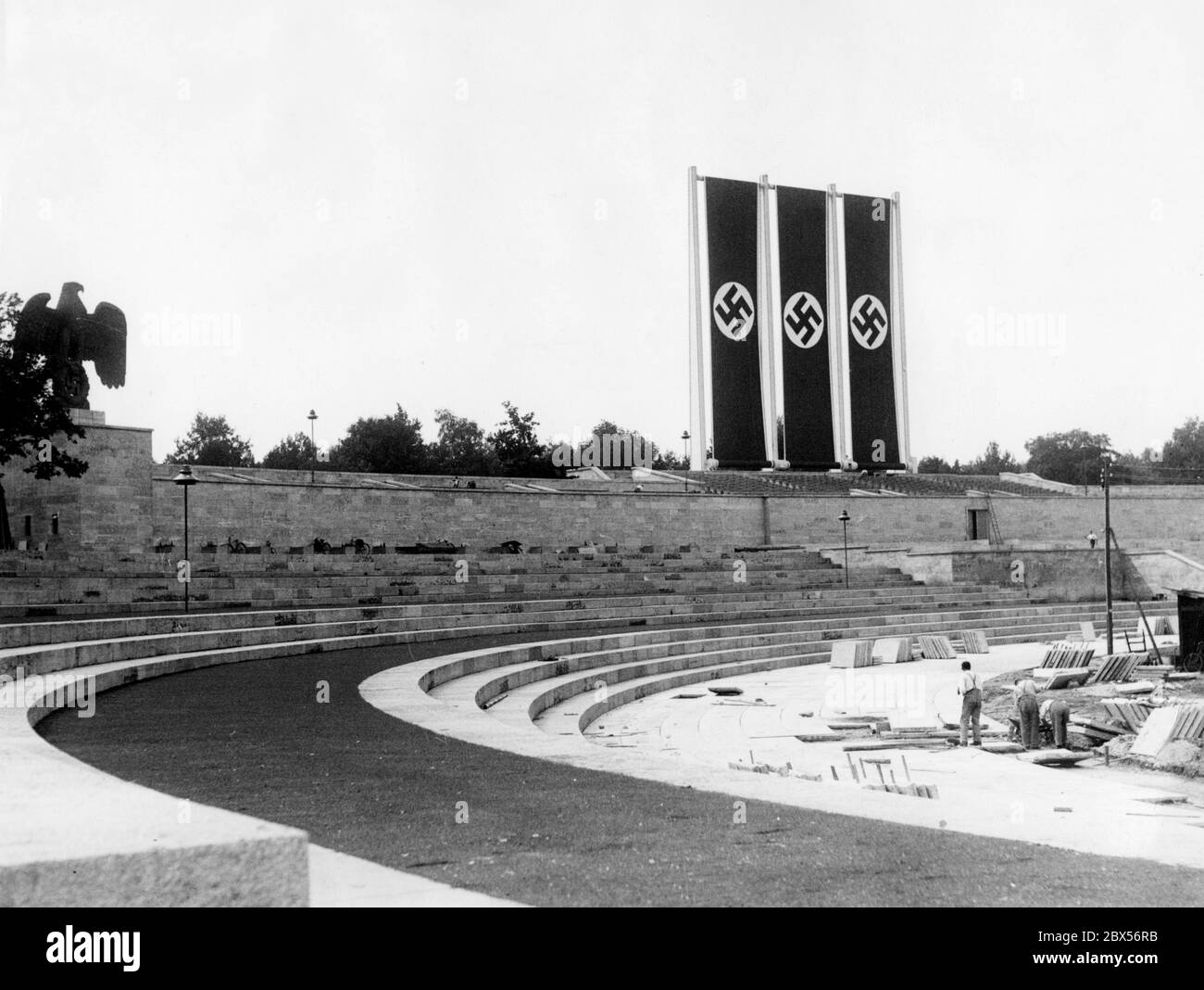 Pendant les travaux de construction à Luitpoldarena, une répétition de drapeau est effectuée avec trois drapeaux swastika pour le Congrès du Parti Reich. À gauche, les symboles souverains : l'aigle impérial avec la croix gammée. Banque D'Images