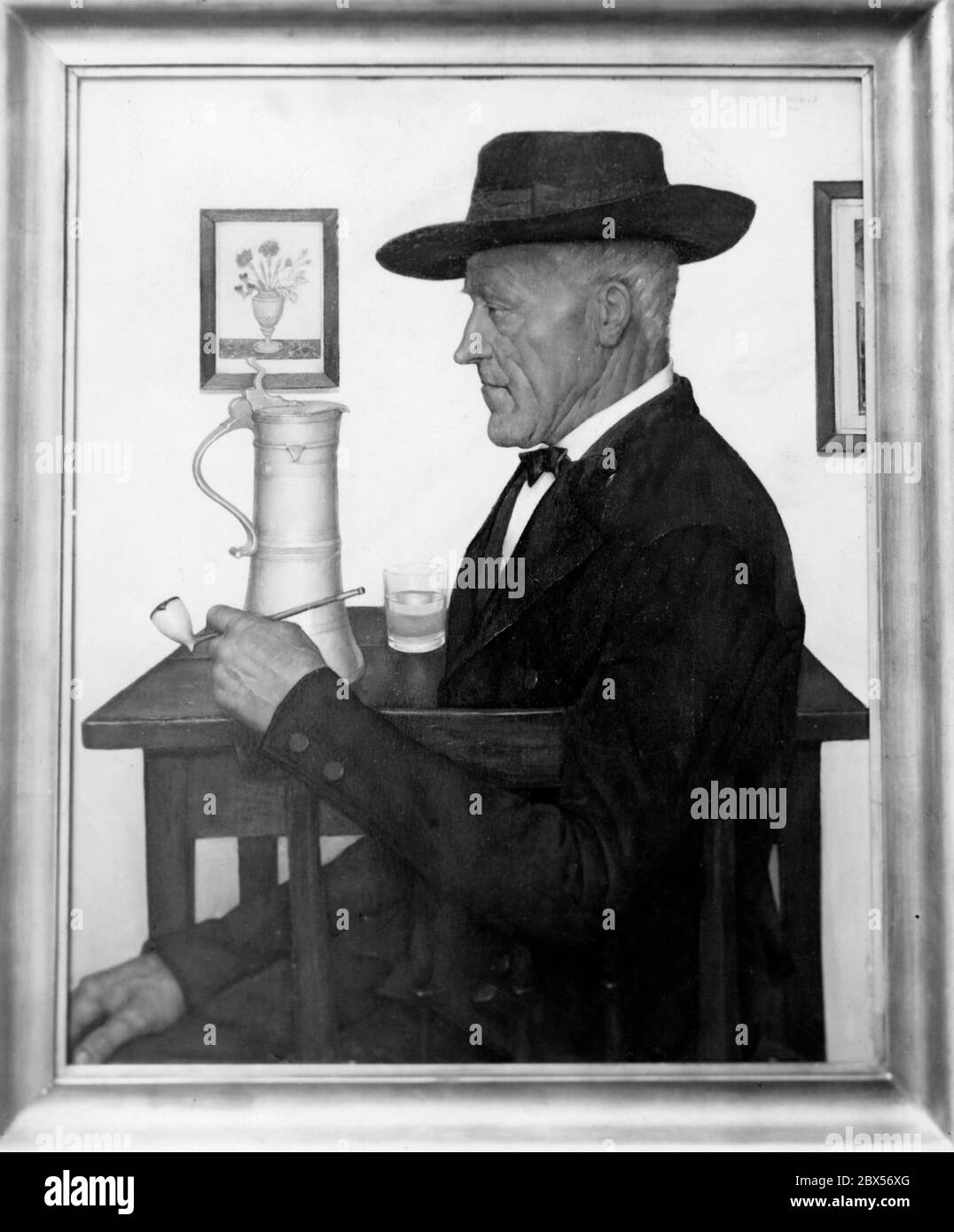 Le tableau 'Elsaessischer Bauer' du peintre G. Stosskopf montre un homme avec un chapeau, assis à une table. Il tient un tuyau dans sa main. Sur la table se trouve une verseuse d'eau et un verre d'eau. Il porte un costume. Sur le mur est accrochée une image avec un vase de fleur. La photo a été exposée à la Kunsthalle de Berlin en 1941 lors de l'exposition 'der deutsche Mensch'. Banque D'Images