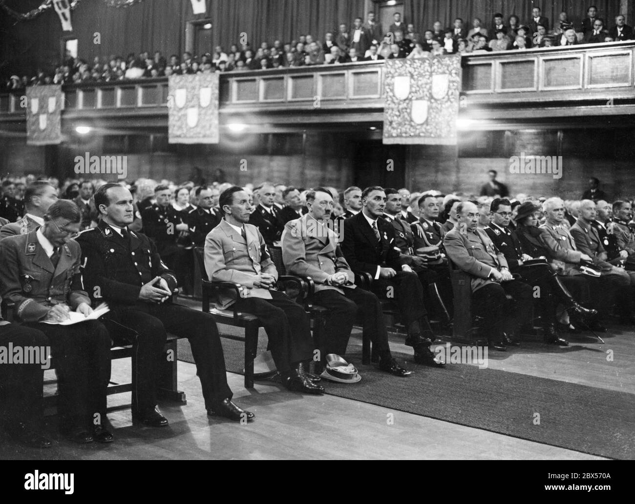 La photo montre les invités d'honneur pendant la session festive de la Chambre des Beaux-Arts de Reich (Reichskunstkammer) dans la salle de cérémonie du Deutsches Museum. De gauche à droite : le maire de Munich Karl Fiehler, le secrétaire d'Etat Karl Hanke, Joseph Goebbels, Adolf Hitler, le professeur Adolf Ziegler (président de la Chambre des Beaux-Arts de Reich), Walther Funk, Philipp Bouhler et probablement Gerdy Troost. À droite de l'image, Heinrich Himmler et Hugo Sperrle. Banque D'Images